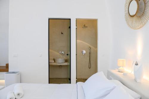 a white bedroom with a shower and a bed at Three Bells Suites in Firostefani