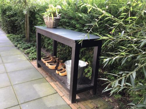 a black table with a bunch of shoes under it at Vakantiehuisje B&B de Kleine Voskuil in Hulshorst