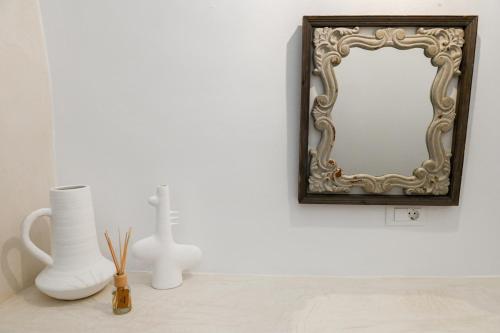 a mirror on a wall next to vases on a table at Three Bells Suites in Firostefani