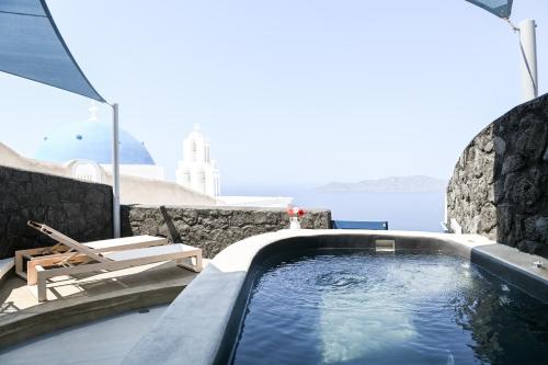 a swimming pool with a view of the water at Three Bells Suites in Firostefani