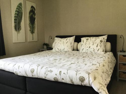 a bed with a white comforter and two pillows at B&B de Kleine Voskuil in Hulshorst