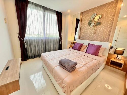 a bedroom with a large bed with purple pillows at EXCESSIVELY 1 Bedroom in Amazon Condo in Jomtien Beach