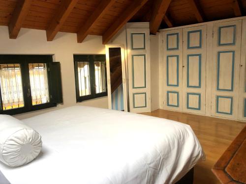 1 dormitorio con cama blanca y ventanas en Sole e Meraviglia en Sesto Calende