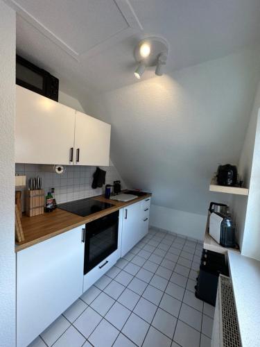 cocina con armarios blancos y encimera en Ruhige, kleine Ferienwohnung, en Schortens