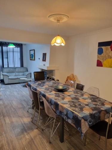 a dining room with a table with chairs and a couch at Maison du port, à 100 m de la mer jusqu'à 9 personnes in Cancale