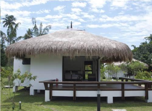a hut with a grass roof with a bench in front at Hijo Resorts Davao in Tagum