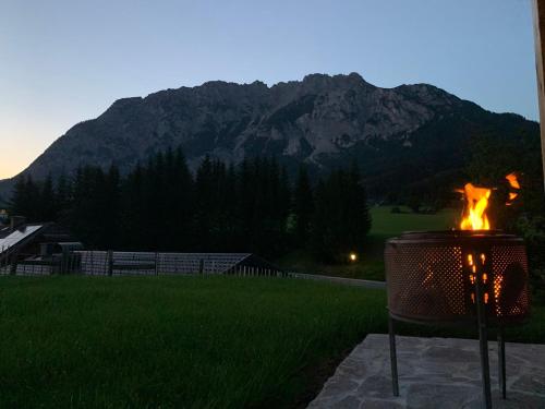 a fire pit in a yard with a mountain in the background at MyHolzhaus - zum Wohlfühlen in Gröbming