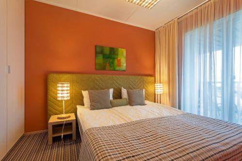 a bedroom with a bed with an orange wall at HYGGE APART with fireplace at the seaside in Kuressaare