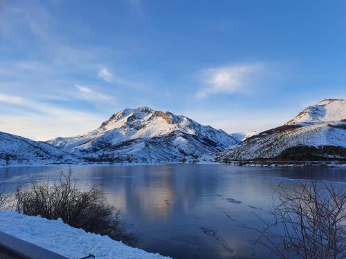 uma vista para um lago com montanhas cobertas de neve em El Sueño de Valcabe em Cardaño de Abajo