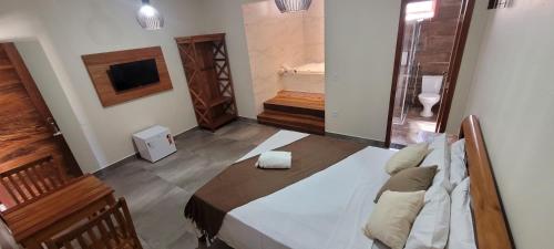 a room with a bed and a bathroom with a television at Pousada Império in Serra do Cipo