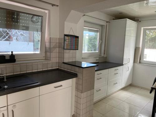 a kitchen with white cabinets and black counter tops at Apartment in Rust