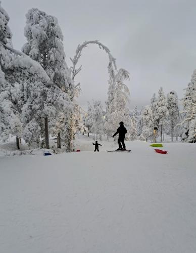 a man and a child are playing in the snow at Apartment Naavis in Rovaniemi