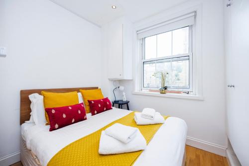 a bedroom with a large bed with yellow and red pillows at One Bedroom Near Russell Square in London