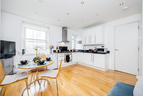 a kitchen with white cabinets and a table and chairs at One Bedroom Near Russell Square in London