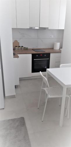 cocina con armarios blancos, mesa blanca y silla en Mia DM Apartment, en Skopje