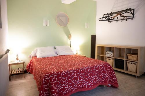 Schlafzimmer mit einem Bett mit einer roten Decke und einem Spiegel in der Unterkunft Hôtel-restaurant le Palais in Apt