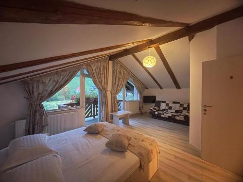 a bedroom with a large bed and a living room at Pensiunea Padurea Verde in Moieciu de Sus