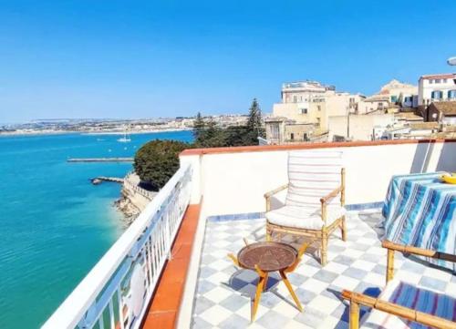 a balcony with a table and chairs and the water at Terrazza sul mare attico "Alfeo e Aretusa" in Siracusa