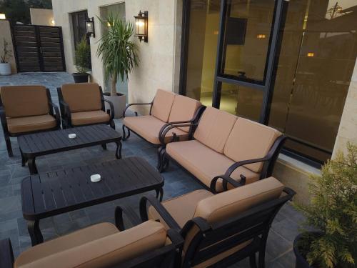 a patio with two chairs and a couch and tables at H Luxury Hotel in Wadi Musa