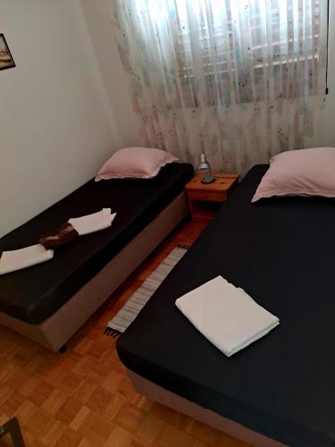 a bedroom with two beds and a window with curtains at Apartman Donna in Zaboric