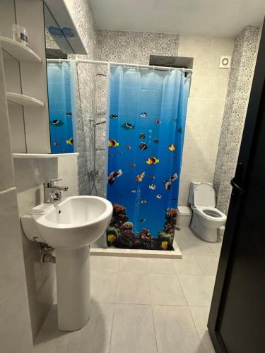 a bathroom with a shower with a fish shower curtain at Private apartment in Tbilisi City