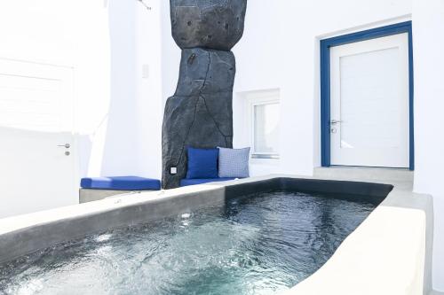 a swimming pool in a white room with a stone pillar at Three Bells Suites in Firostefani