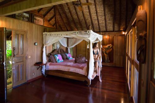 a woman standing in a bedroom with a canopy bed at Rohotu Fare in Bora Bora