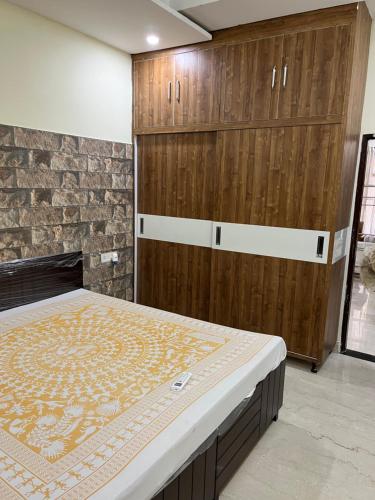 - une chambre avec un grand lit et des placards en bois dans l'établissement Hare Krishna Flat, à Kharar