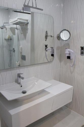 a white bathroom with a sink and a mirror at White Line Boutique Hotel in Elazığ
