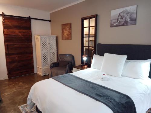 a bedroom with a large white bed and a chair at The Oak Tree in Queenstown