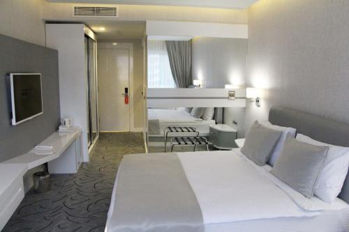 a hotel room with a large white bed and a mirror at White Line Boutique Hotel in Elazığ