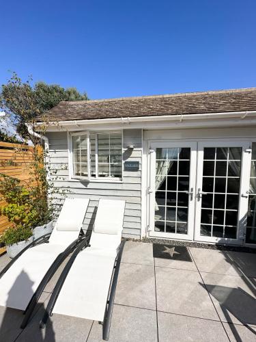 a group of white benches in front of a house at 1 Bed Cabin - Sleeps 2 - Pets - Garden - Parking in South Hayling