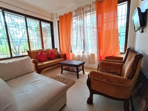 a living room with a couch and chairs and windows at Dwarka Holiday Home in Murbād