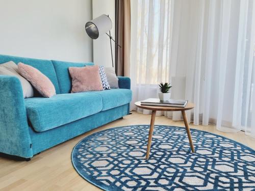 a living room with a blue couch and a table at MELODIJA apartments in Druskininkai center in Druskininkai
