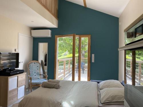 Dormitorio con pared azul, cama y TV en Appartement climatisé avec terrasse, en Cours la Ville