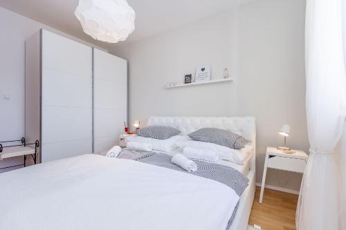 a white bedroom with a white bed and a window at Apartment Pineta in Fondole