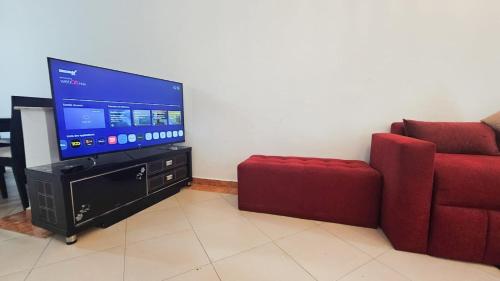 een woonkamer met een flatscreen-tv en een rode bank bij Appart Malabata au Bord de la Mer in Tanger