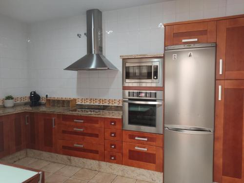 La cuisine est équipée d'armoires en bois et d'un réfrigérateur en acier inoxydable. dans l'établissement Casa Almazara, à La Puebla de Cazalla