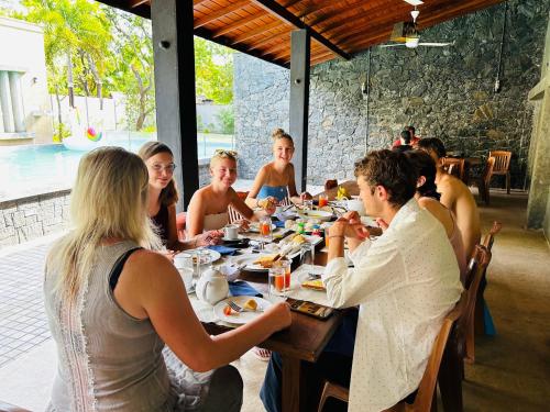 un grupo de personas sentadas en una mesa comiendo comida en Royal Nest en Polonnaruwa