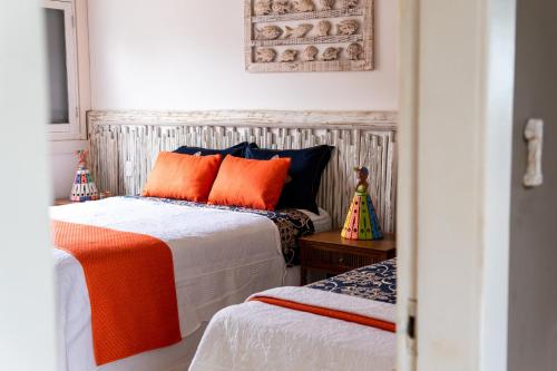 a bedroom with two beds with orange pillows at Casa Mandala Corumbau in Corumbau