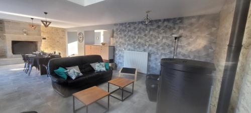 un salon avec un canapé noir et une table dans l'établissement Belle maison en pierre avec cour, à Huberville