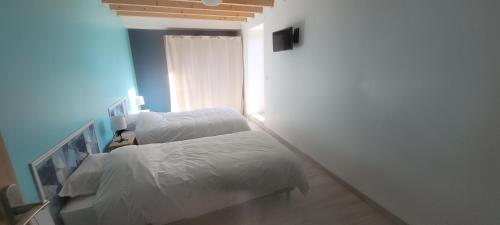 a bedroom with two beds with white sheets at Belle maison en pierre avec cour in Huberville