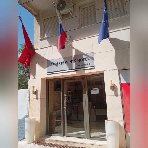APPARTEMENTS HOTEL PYRAMIDES في تازة: فندق فيه رايات معلقه خارجه