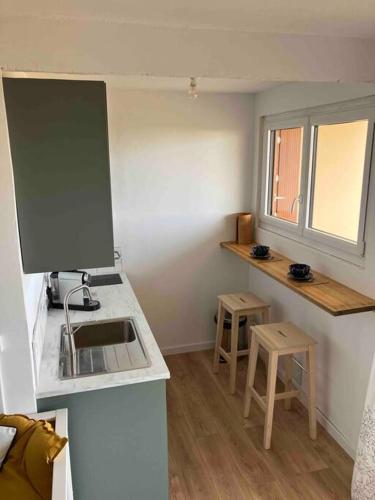 a kitchen with a sink and a counter with two stools at Studio vue sur l’océan in Saint-Brevin-les-Pins
