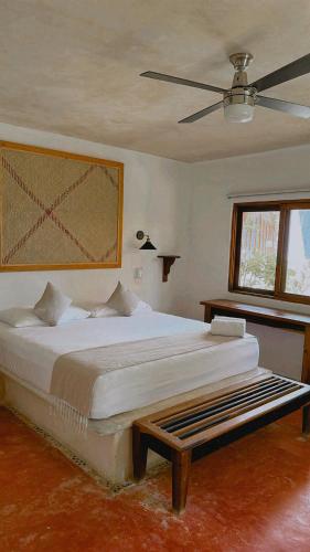 a bedroom with a large bed and a ceiling fan at La Conchita Tulum in Tulum