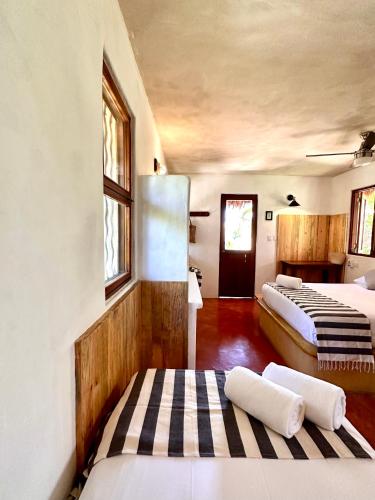 a room with two beds and a hallway with windows at La Conchita Tulum in Tulum