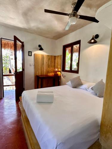 a bedroom with a large white bed with a ceiling fan at La Conchita Tulum in Tulum