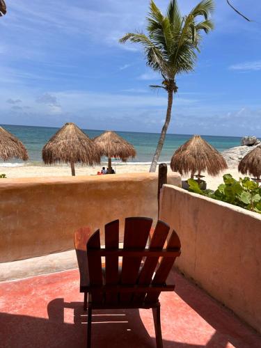 a beach with a chair and some straw umbrellas at La Conchita Tulum in Tulum