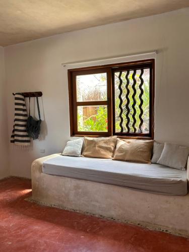 a bed in a room with a window at La Conchita Tulum in Tulum
