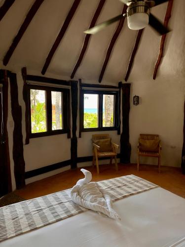 a bedroom with two beds in a room with windows at La Conchita Tulum in Tulum